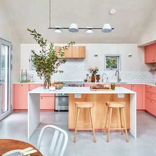 White kitchen with vivid pink cupboards and a modern white island