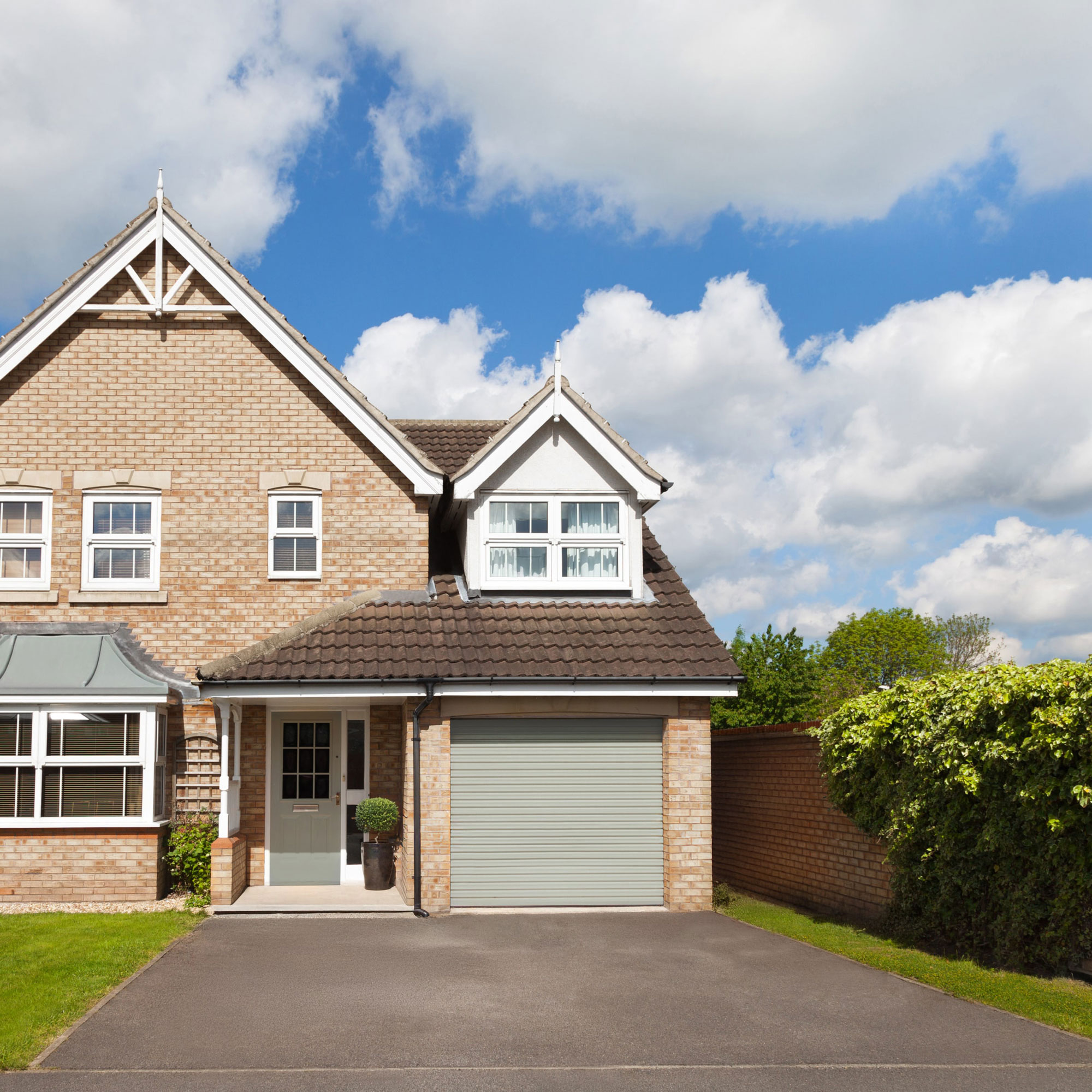 small sloping tarmac driveway with roller garage door