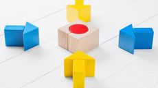 Four blue and yellow arrows point to a wooden block with a red circle in the center. 