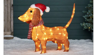 A light-up Daschund Christmas decoration, wearing a Santa hat and a woolly scarf.