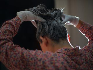 Woman rubbing hair dye into her hair - how to get hair dye off skin