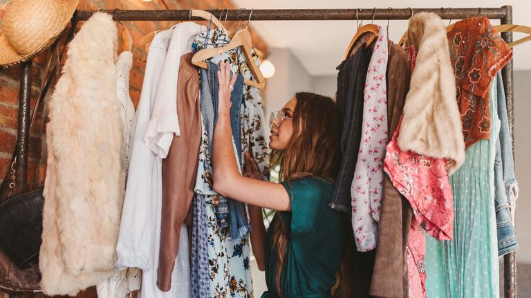 best dresses – woman hangs clothes on rack at home