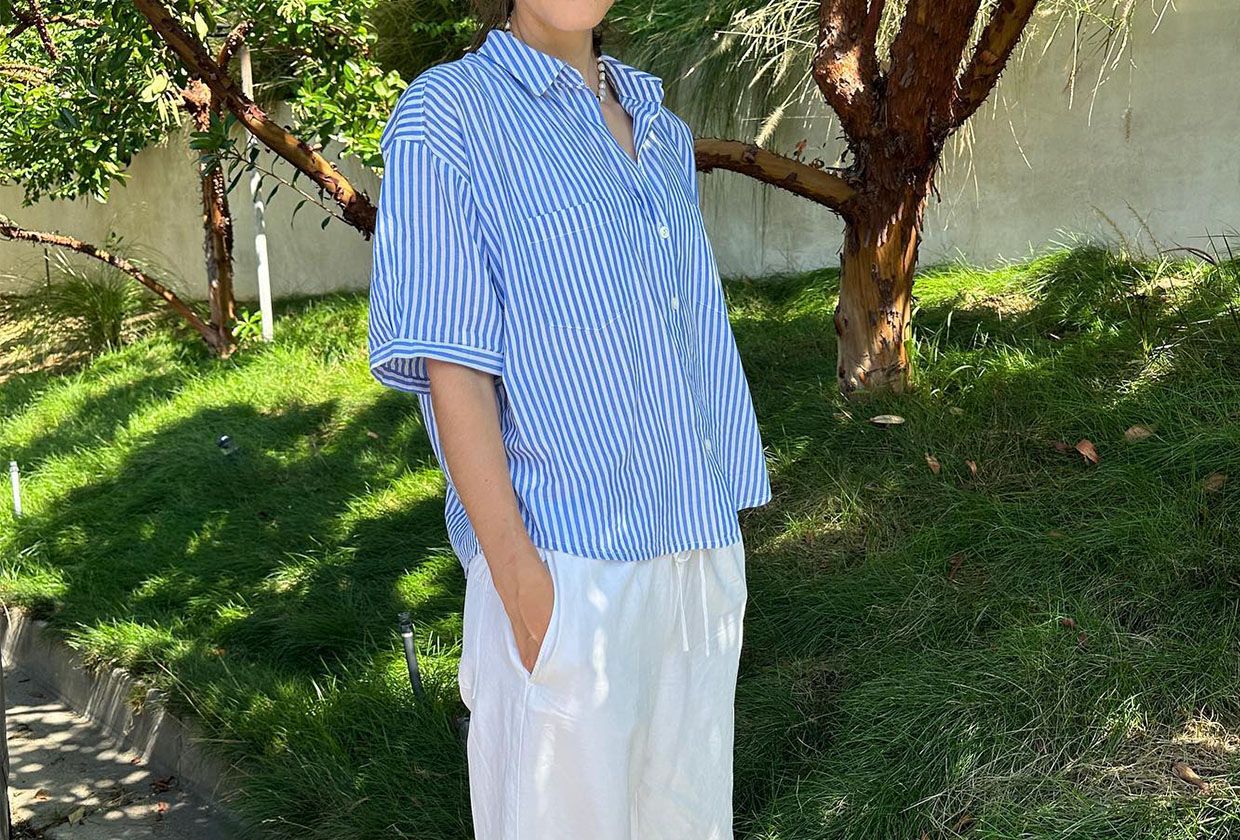 Woman in blue and white shirt and white linen pants