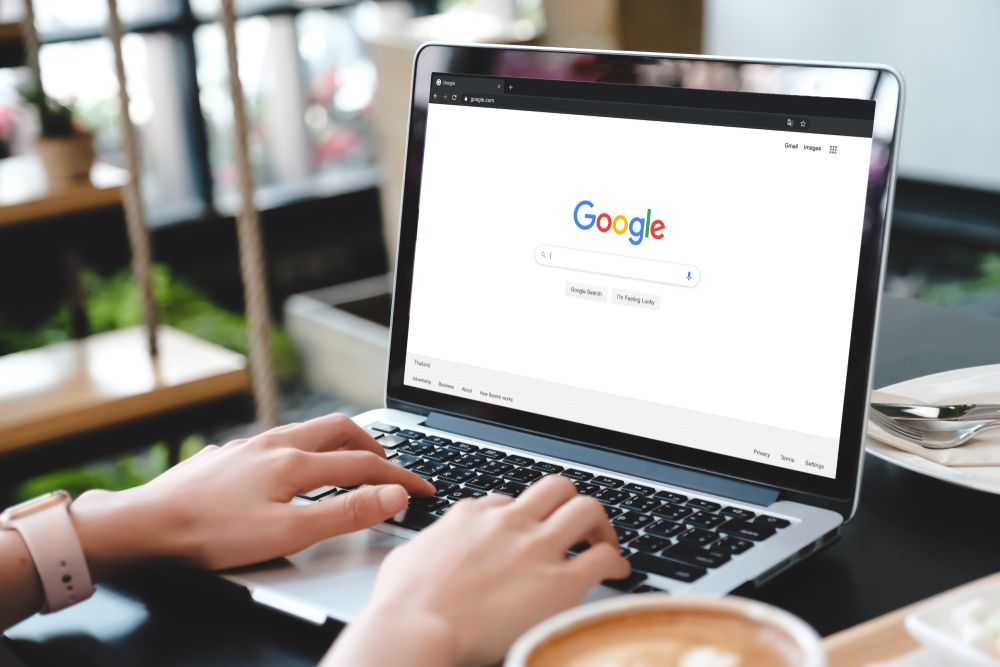 Image of a person using Google Search on a laptop, sitting in a cafe