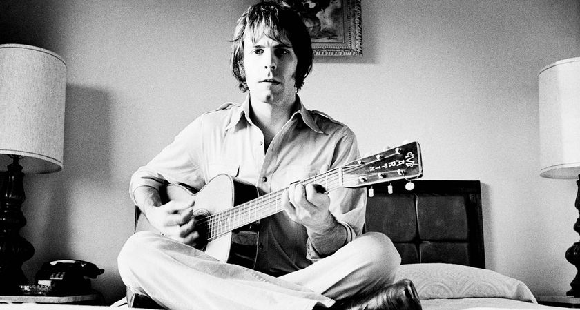 Bob Weir sits cross-legged on hotel room bed and strums his Martin acoustic