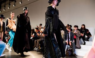 Models wear black dresses and coats with hats