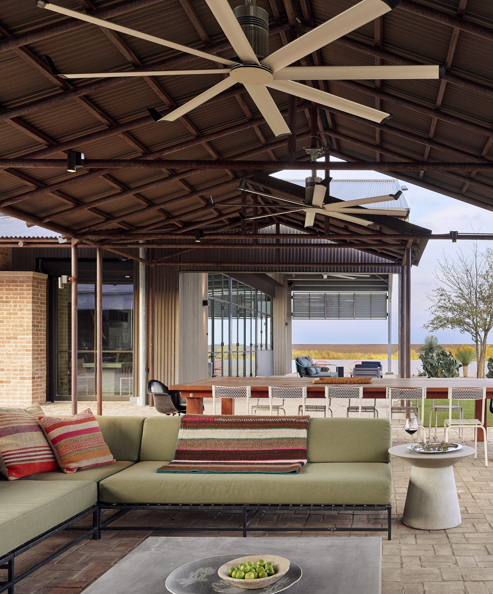 outdoor living room with green sofas and striped cushions and throws