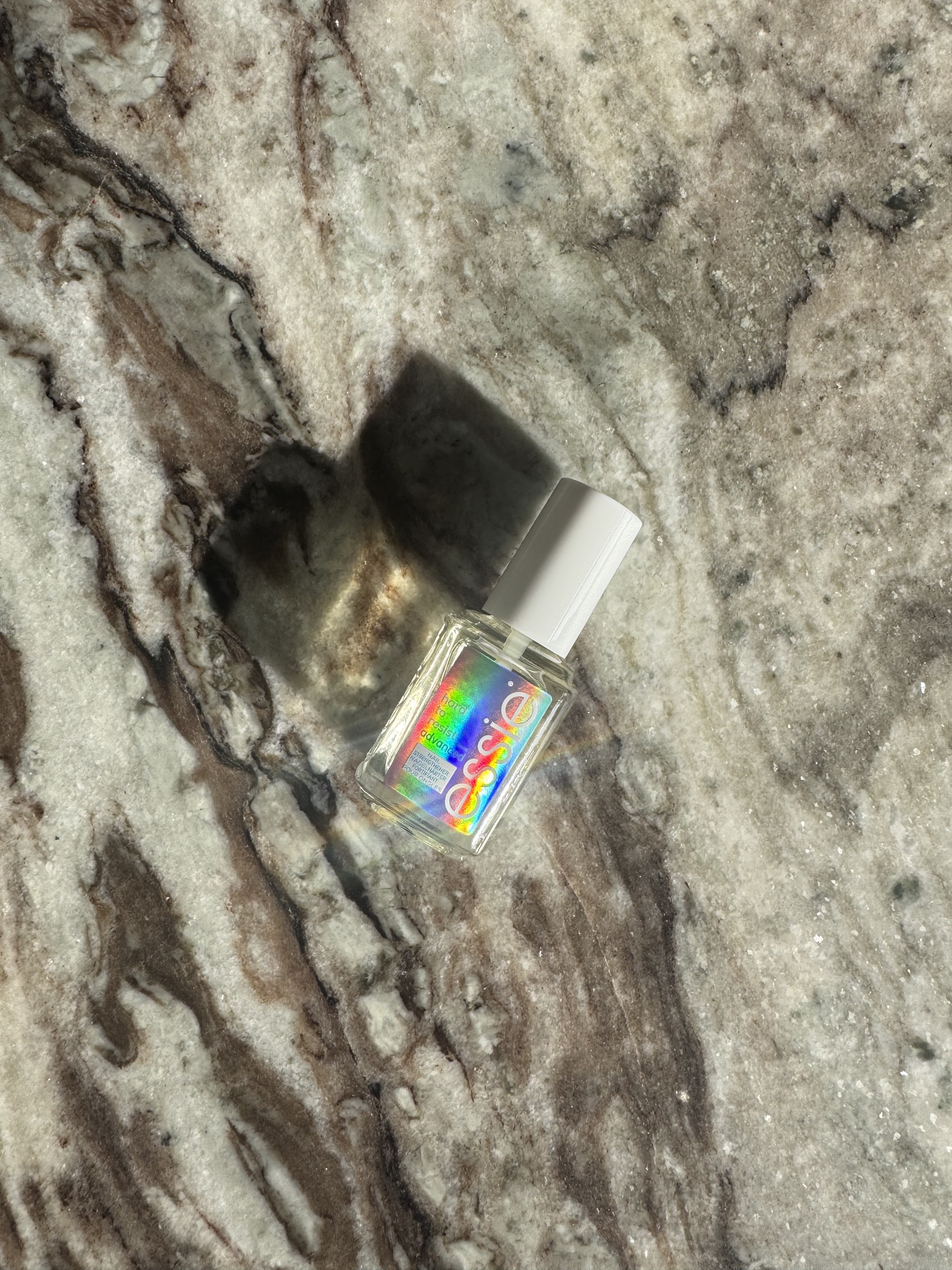A bottle of Essie Hard to Resist Nail Strengthener in Clear on a marble table