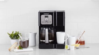 How to clean a Cuisinart coffee maker: Cuisinart's drip coffee maker on a white countertop with a carafe of coffee and mugs around it