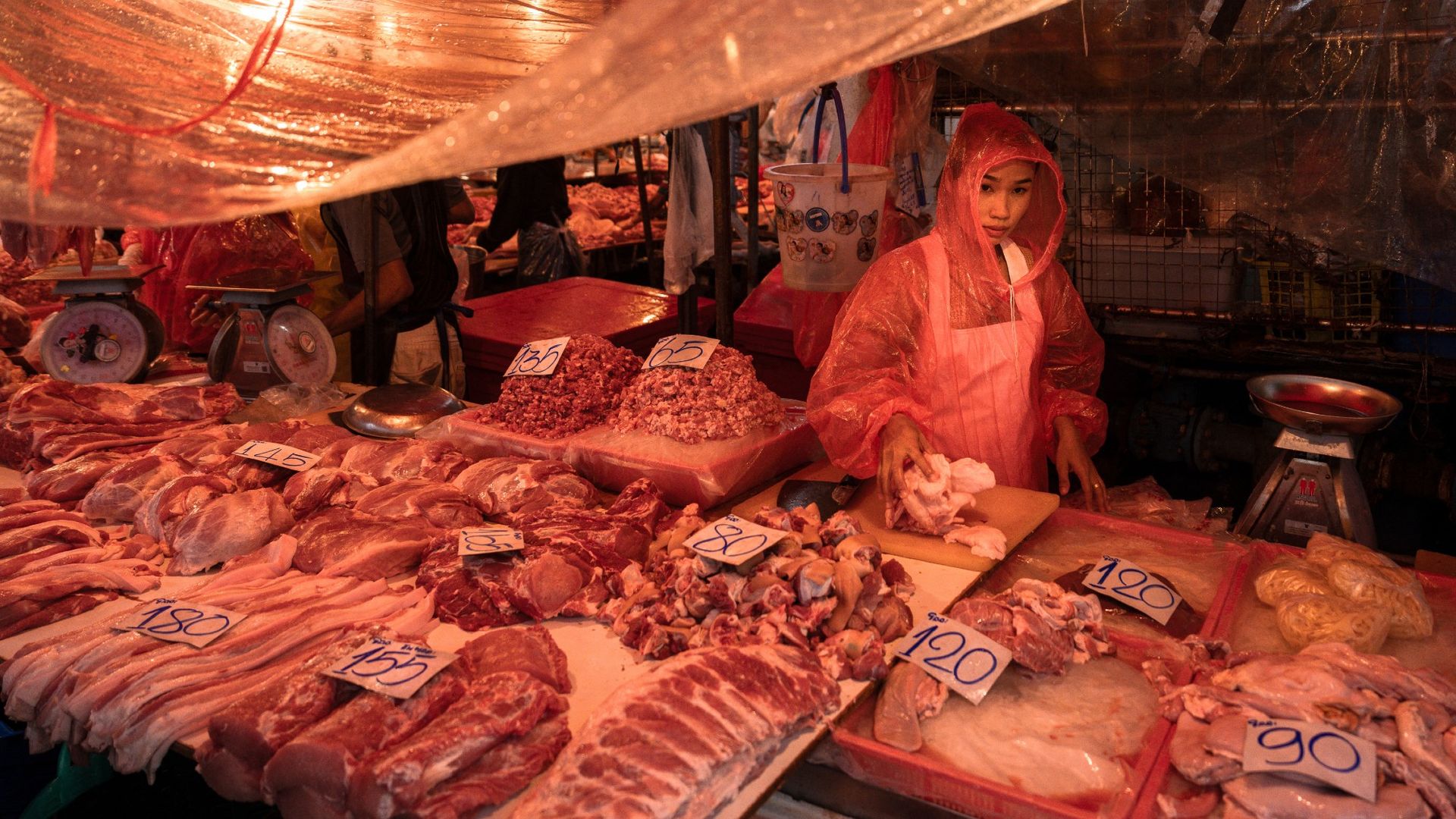 
                                A meat seller tries to stay dry during a downpour at Bangkok&#039;s open-air Khlong Toei Market in Thailand
                            