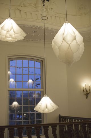 Three white silk lights hang from an ornate, domed ceiling
