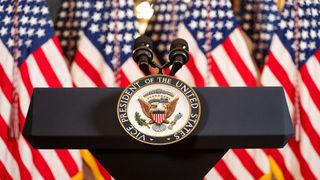 speaker&#039;s lectern showing office of the president of the united states in front of american flags