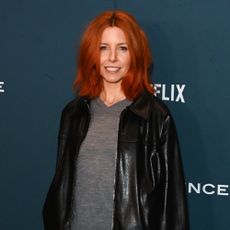 Stacey Dooley on the red carpet wearing a leather jacket and a grey V-neck sweater
