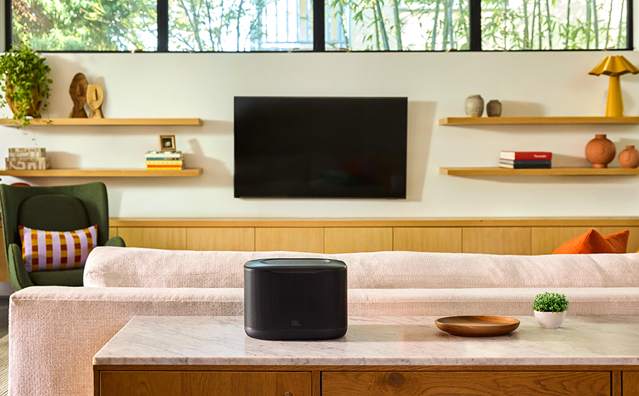 JBL Cove X1 placed on a unit behind a sofa.