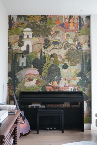 A music room with a piano, a guitar and a bright fantasy themed mural accent wall