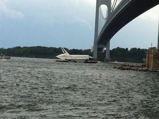 A barge carrying NASA's space shuttle Enterprise prototype passes beneath a bridge in the New York Harbor during a trip from John F. Kennedy airport to a New Jersey port during delivery on June 3, 2012.
