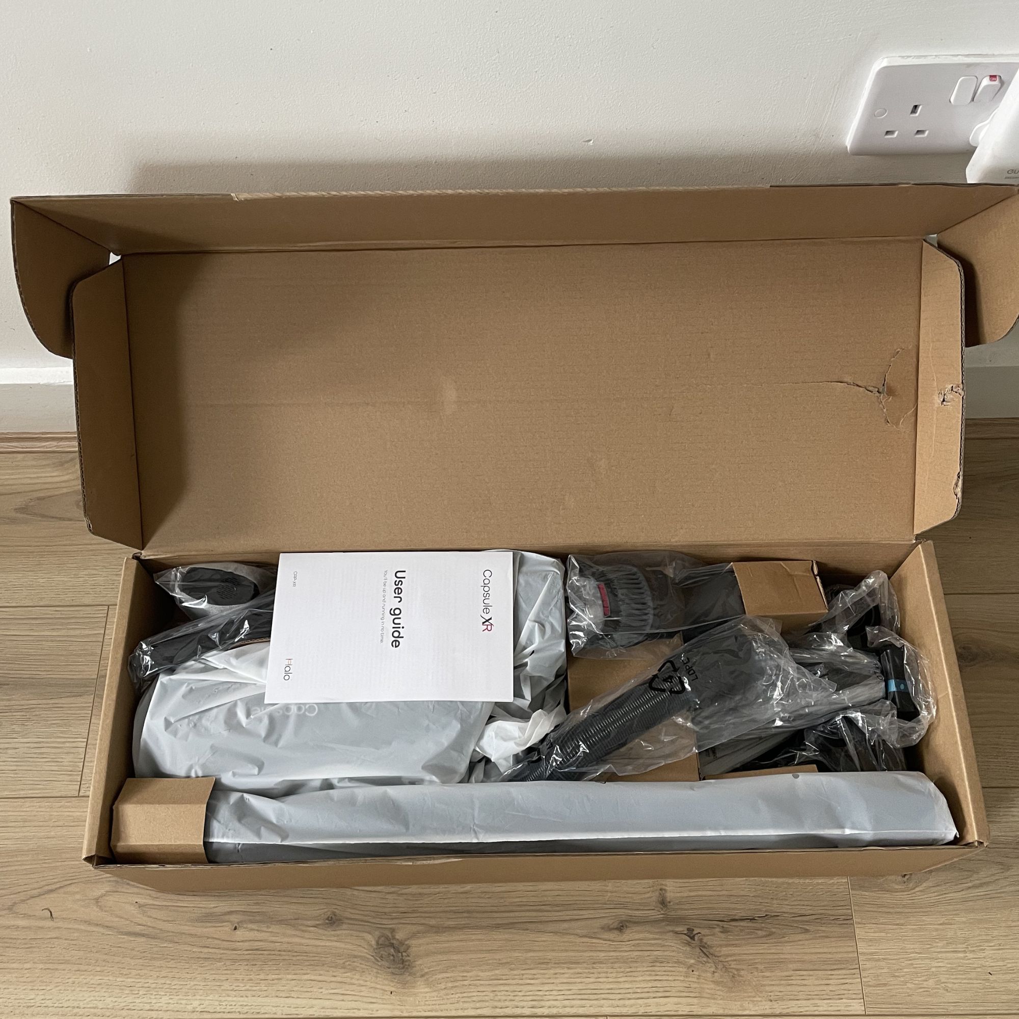 Halo Capsule XR Cordless Vacuum Cleaner box with the lid open, showing the packaged contents inside
