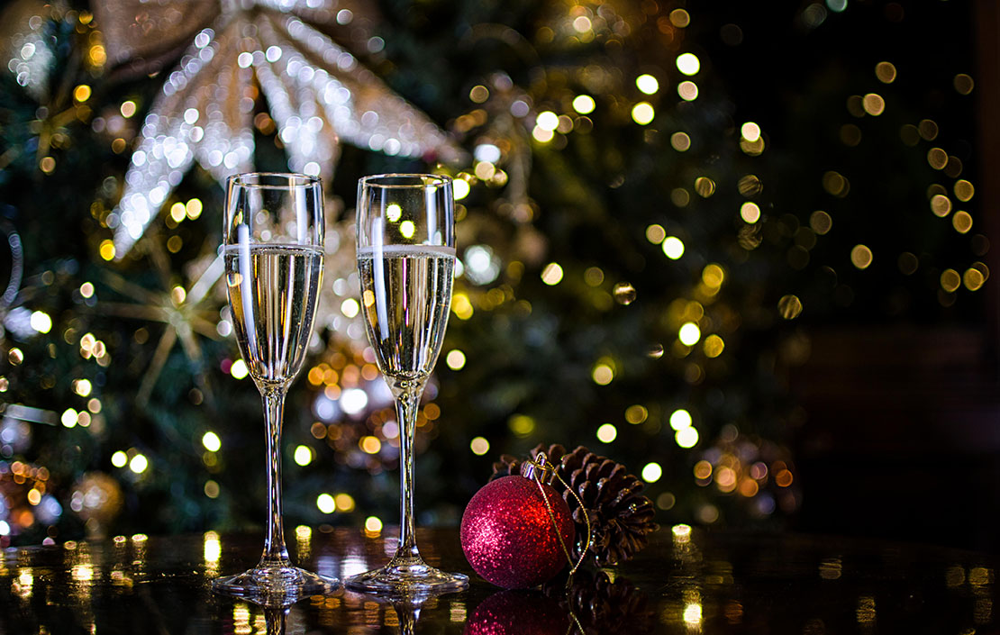 Two Champagne Glasses surrounded by Christmas Decorations