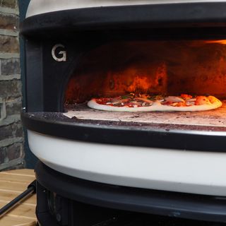 A close up of an uncooked pizza in the Gozney Dome pizza oven