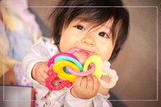 A close up of a baby with teething rings in its mouth