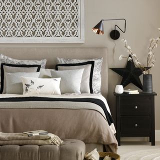 bedroom with cream wall and black trim cushion covers with bedside table