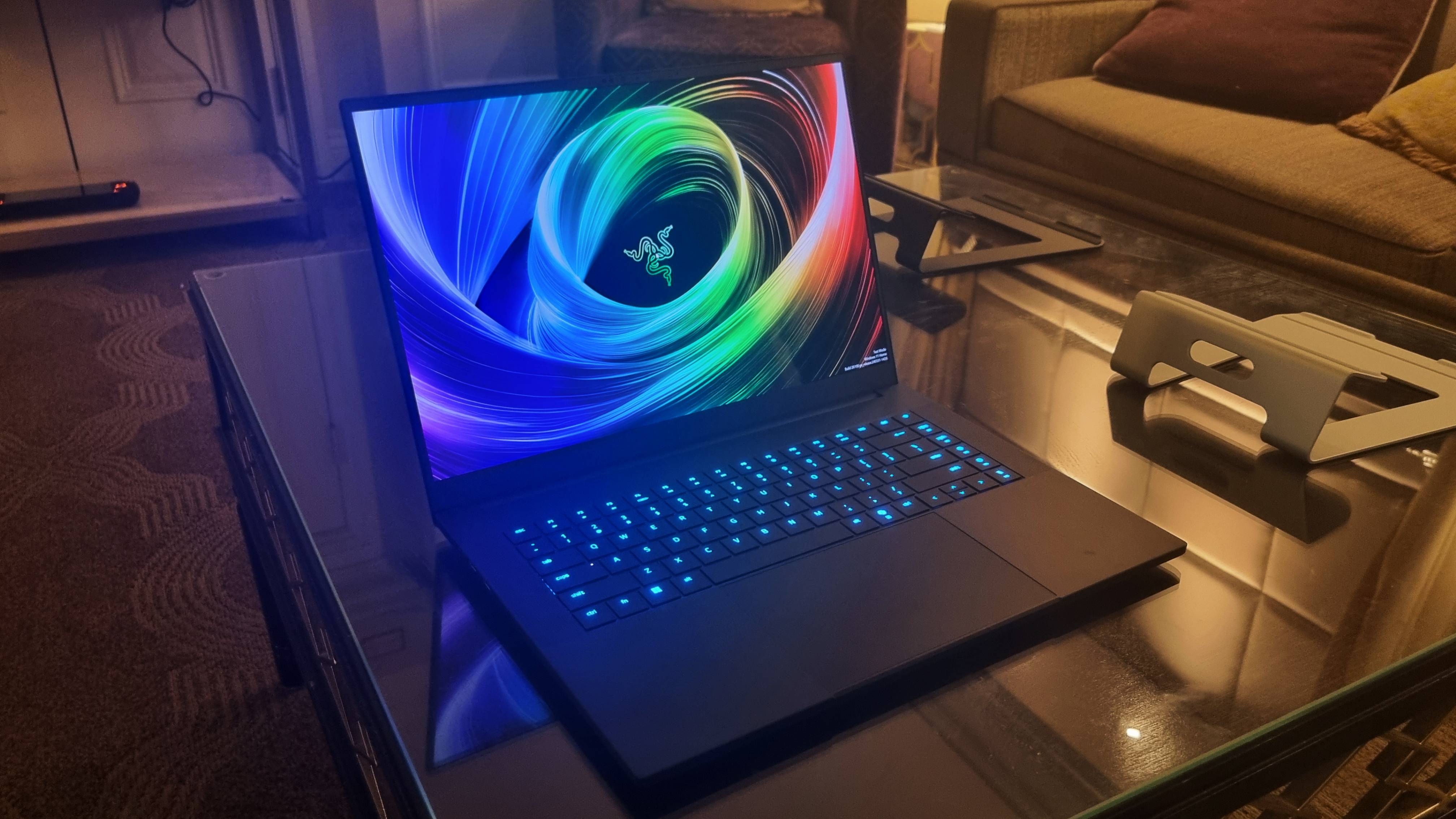 The Razer Blade 16 at CES 2025, on a glass table and with its keyboard lit up in blue.