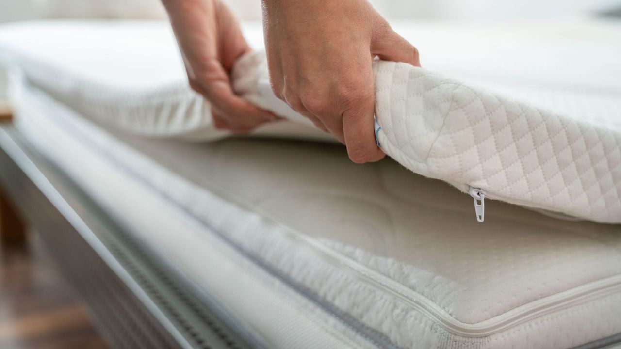 Mattress topper being laid on top of a mattress 