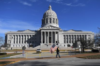 A man waves and American flag as he walks outside the Missouri State Capitol building on January 20.