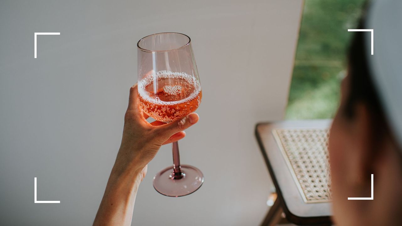 Woman&#039;s hand holding up a glass of non-alcoholic sparkling water with cordial, representing the benefits of cutting back on alcohol in menopause