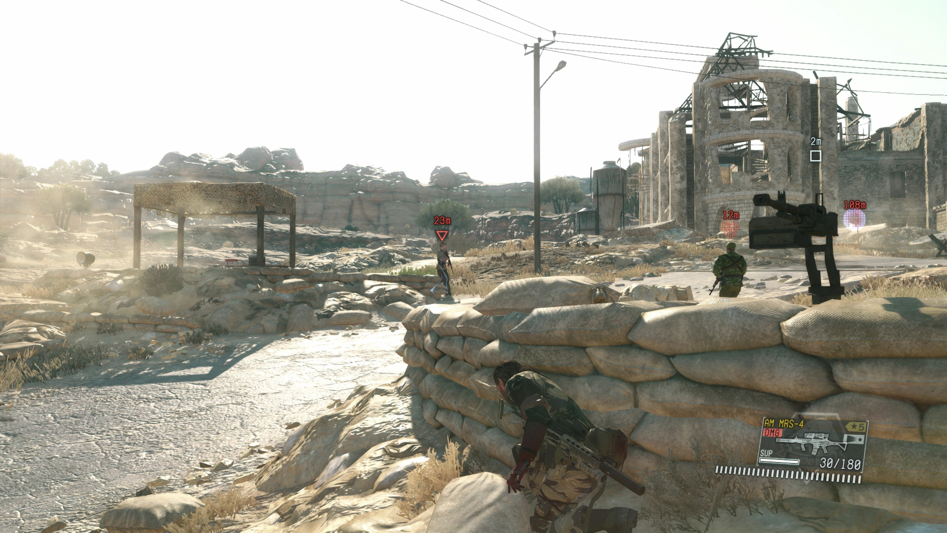 Metal Gear Solid 5 screenshot showing Snake taking cover behind some sandbags