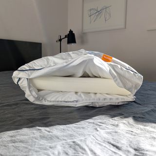 The Emma Original Hybrid Pillow being tested on a bed with a grey linen duvet cover