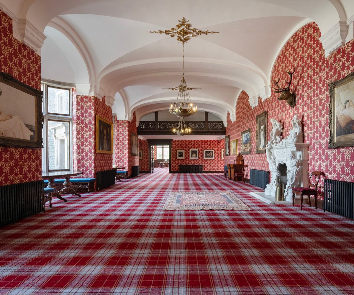 The entrance to the home includes candle-lit chandeliers and a long chequered carpet with two large balcony windows