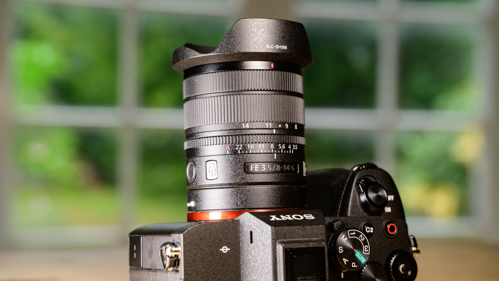 Sony FE 8-14mm F3.5 G fisheye lens attached to a Sony A7R V camera, on a wooden table
