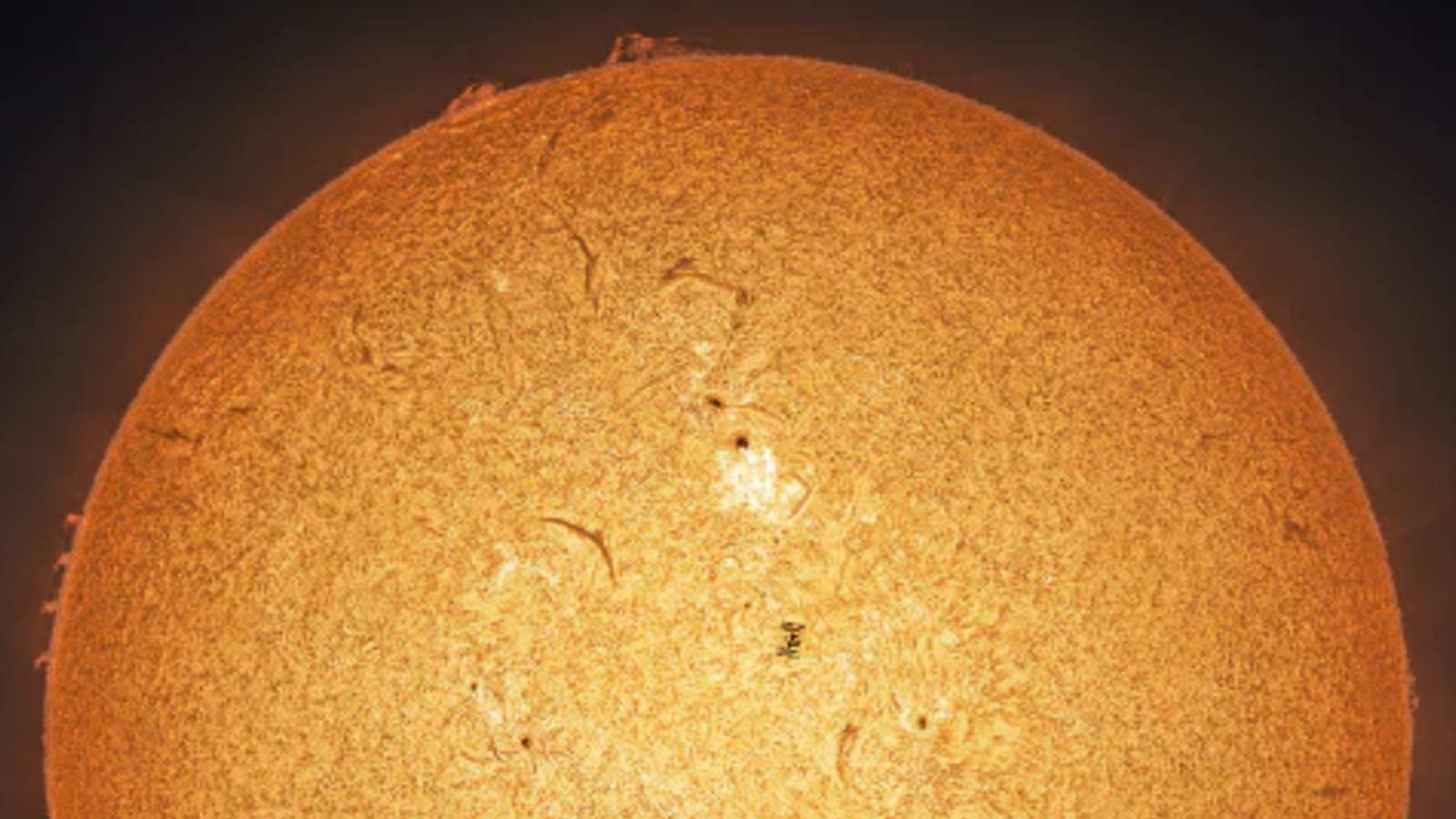 Zoomed out photo of the ISS transiting the sun during a solar flare