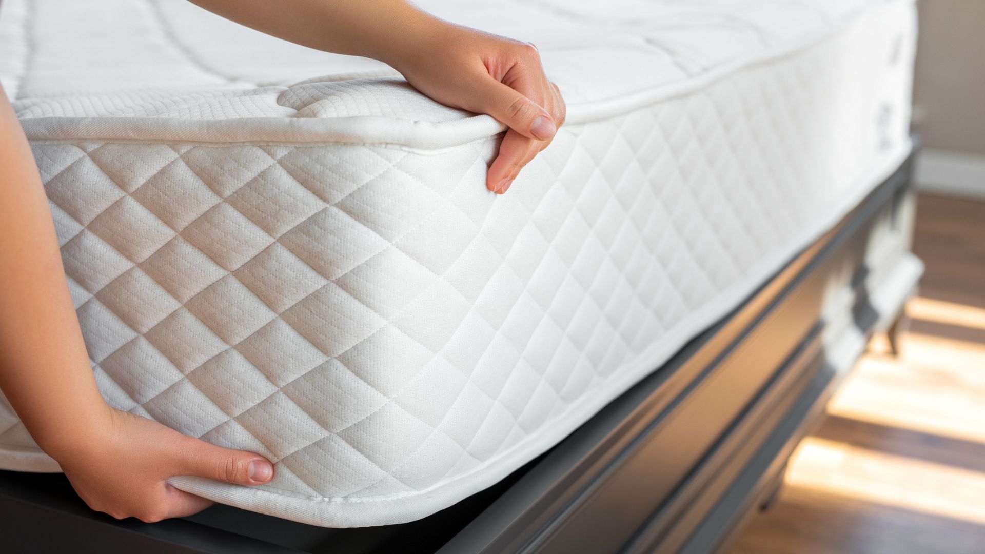 A man lifts the corner of a white mattress to check the quality