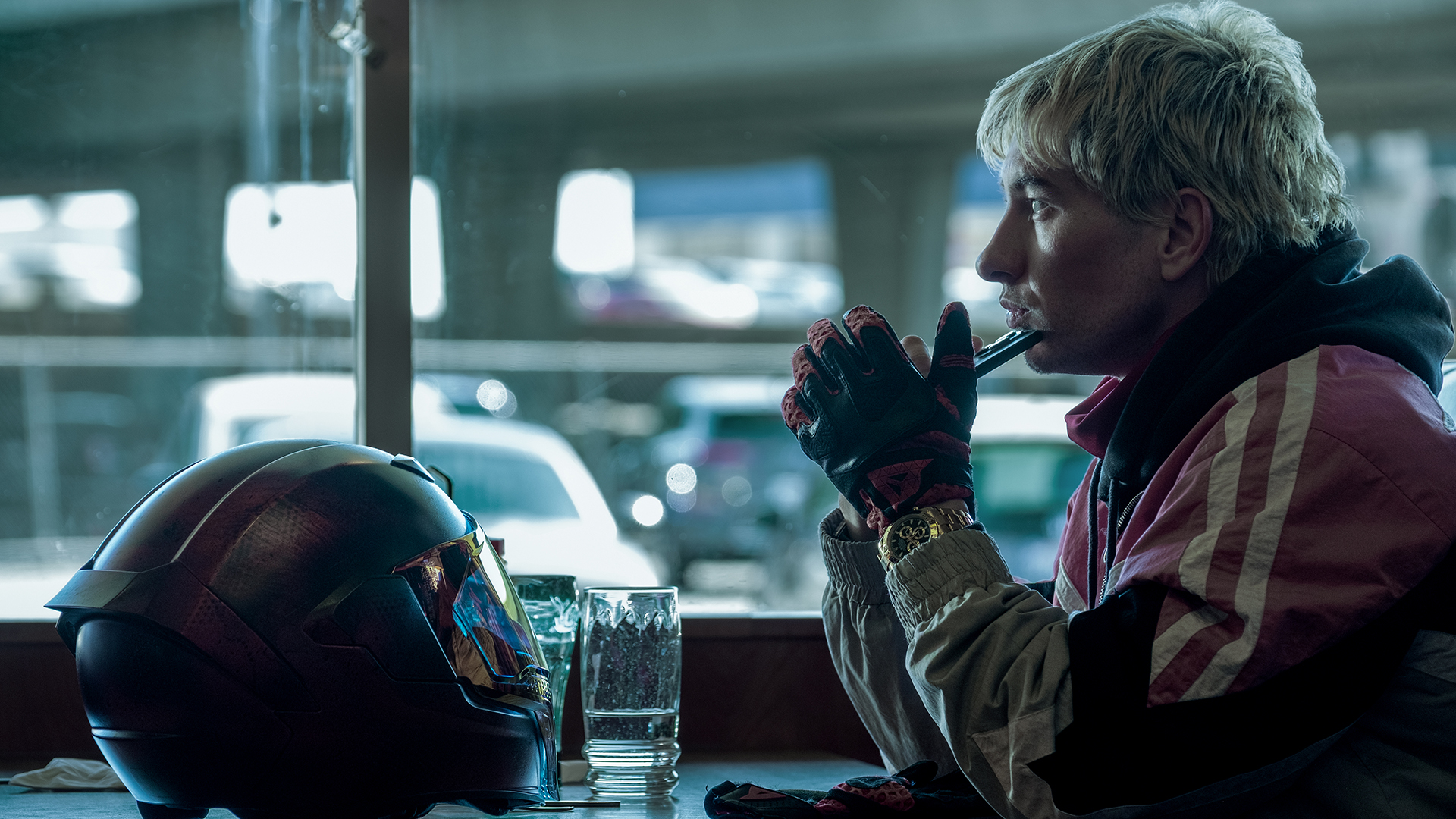 Ormon sitting in a diner with his bike helmet resting on a table in Crime 101