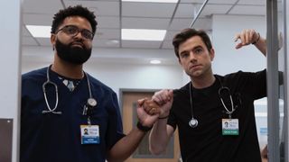 Langdon fist bumps a male nurse while leaning on a door frame