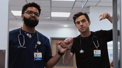 Langdon fist bumps a male nurse while leaning on a door frame
