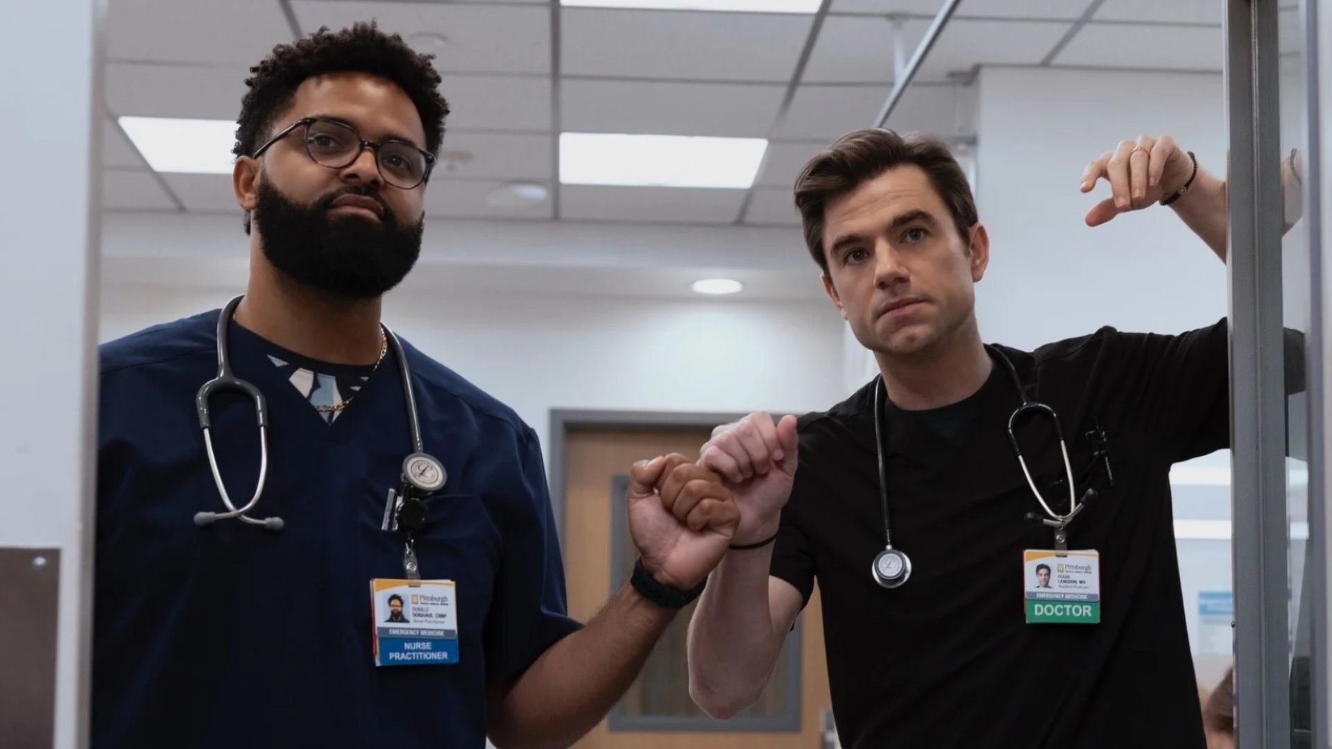 Langdon fist bumps a male nurse while leaning on a door frame