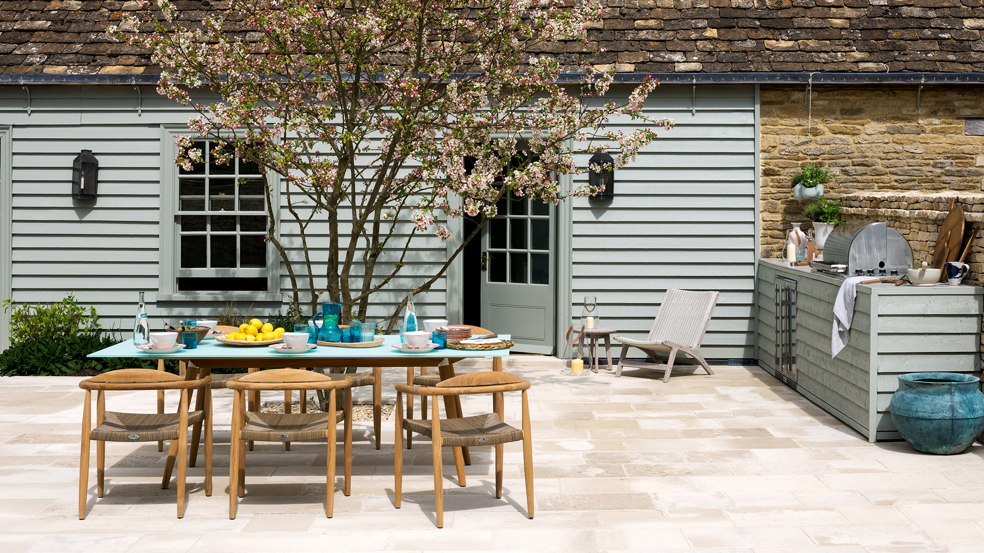 grey wooden clad house with an outdoor dining table and outdoor kitchen