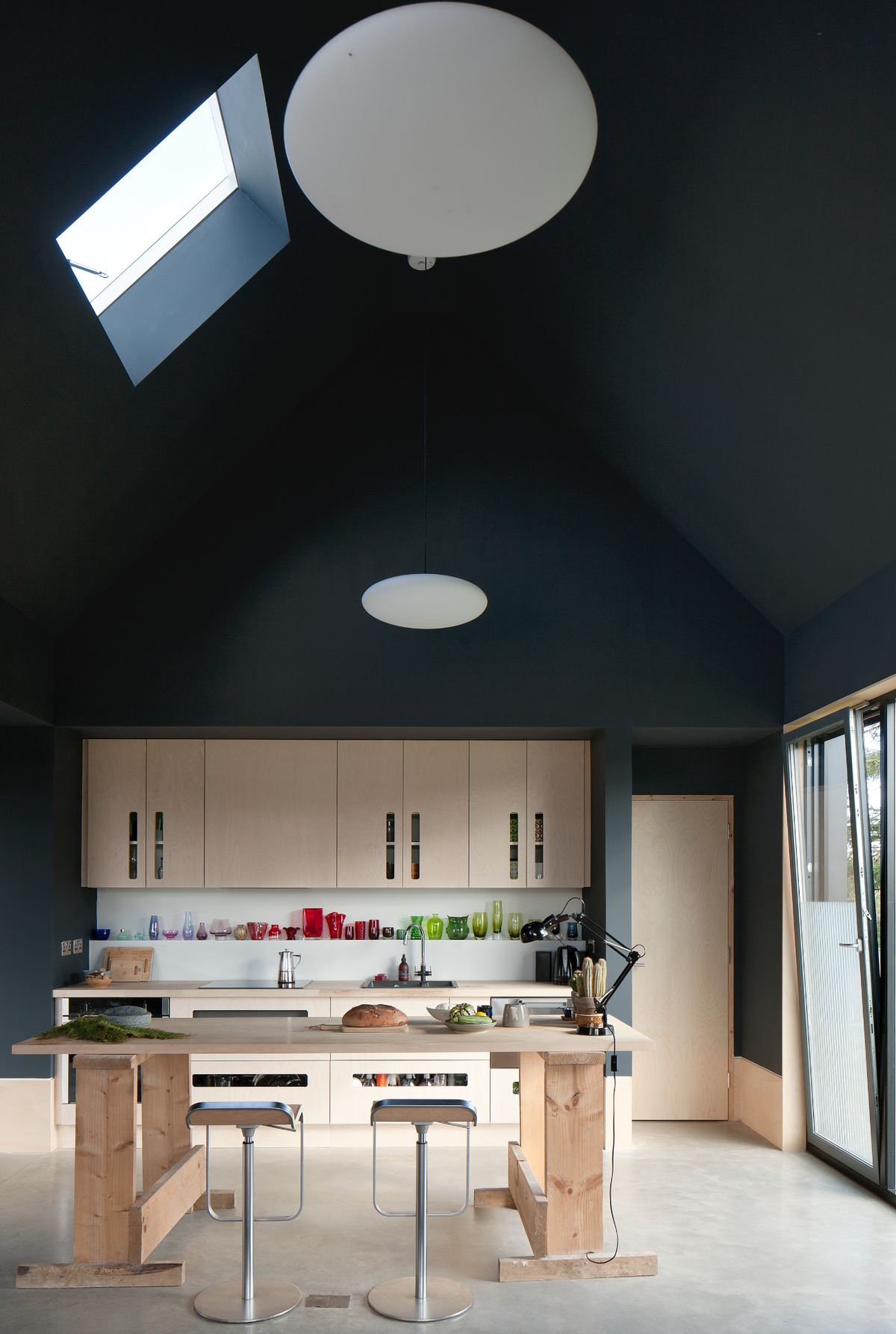A kitchen with plywood fittings, a vaulted ceiling and black walls