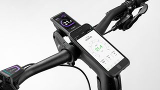 The handlebars of a bike with bike computer and phone integrated in
