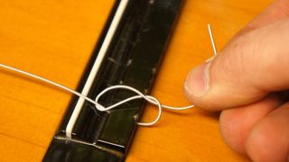 Secure the string tail on a classical guitar