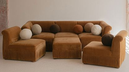 a rust color pit sofa with round ball pillows