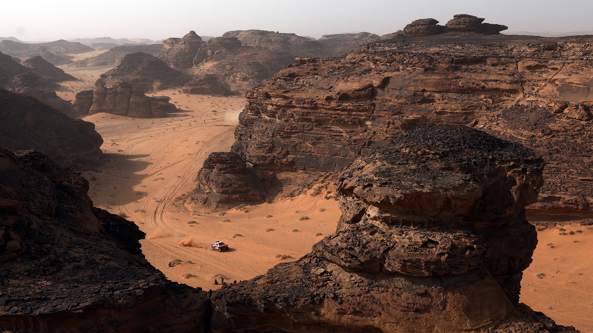 A car skirts enormous sandstone formations during Stage 3 of the Dakar Rally, near AlUla, Saudi Arabia