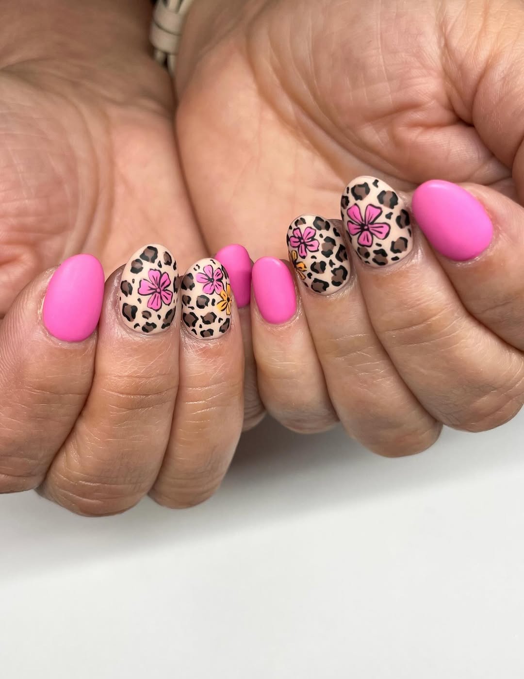 leopard nails with hot pink accent nails and a flower design