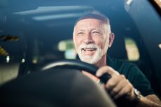 Smiling older man driving car.