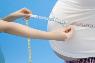 An obese man has his waistline measured.