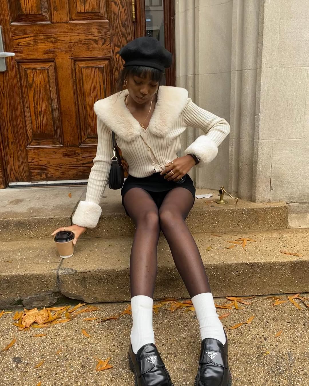 @chanelmckinsie wears a pair of black loafers and white socks with a faux-fur trimmed cardigan and black miniskirt