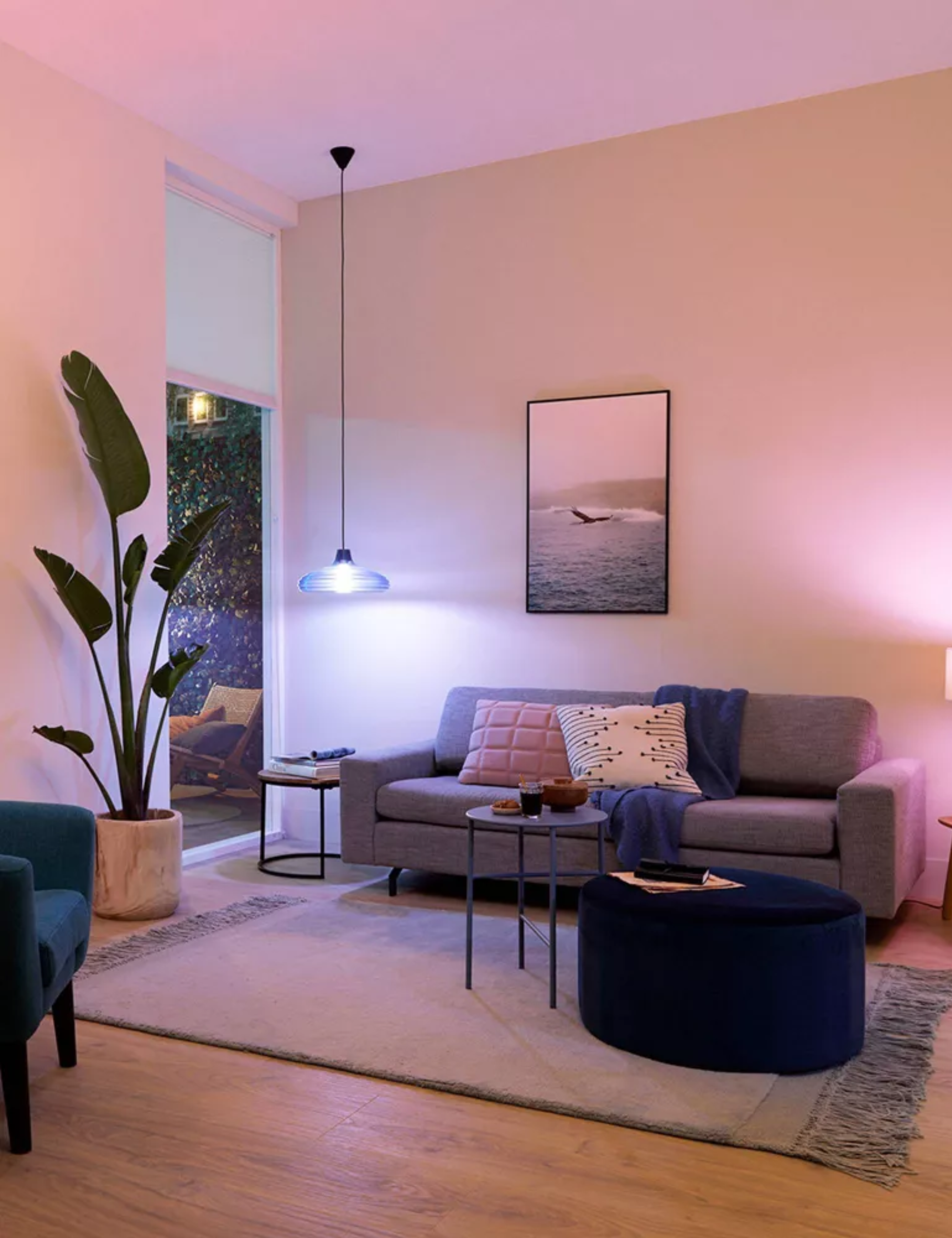 Moody living room area aglow with a pendant light fixture outfitted with a blue color changing blub